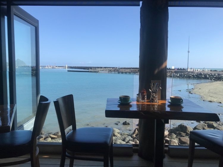 The view from a cafe out open floor-to-ceiling windows over the sea.