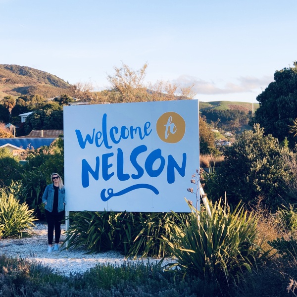 An outdoor "Welcome To Nelson" on a sunny day.