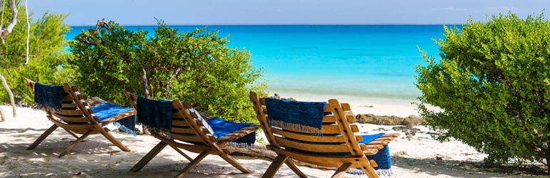 Three beach chairs sitting on a with sandy beach looking out over blue water