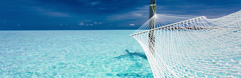 An empty hammock over the shallow azure waters of a lagoon
