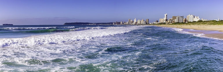 Waves breaking at a beach with a city in the background