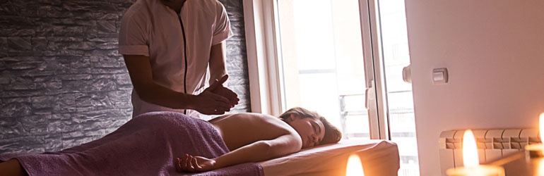 A person getting a massage with candles in the room