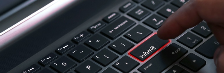 A person pressing a submit key on a laptop