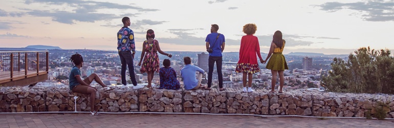 A group of people standing on a ledge overlooking a city