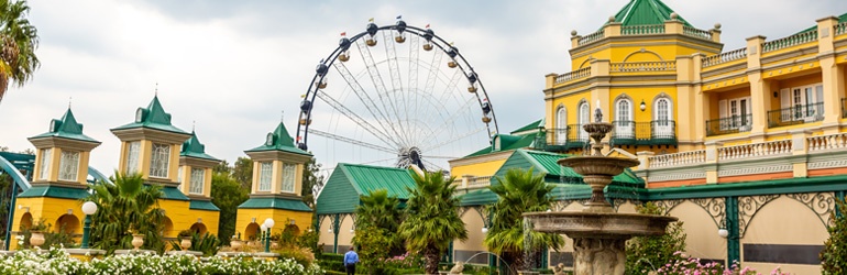 A ferris wheel behind yellow buildings