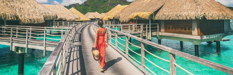 A person walking along a bridge in the Maldives past an overwater Bungalow