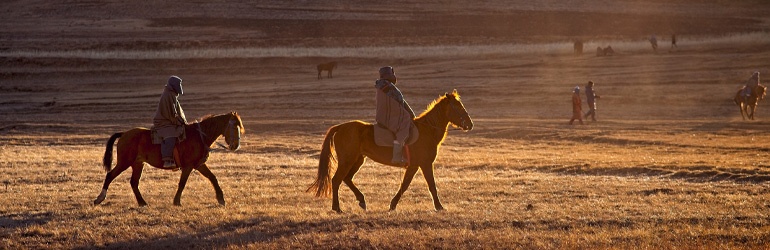two people riding horses in dusty surrounds 