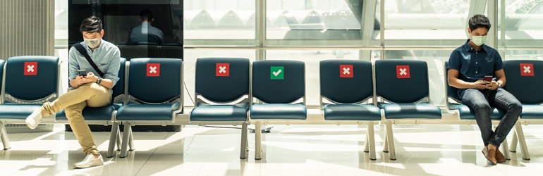 Men practicing social distancing at the airport