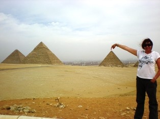 A person taking a photo that makes it look like they are touching the top of a pyramid